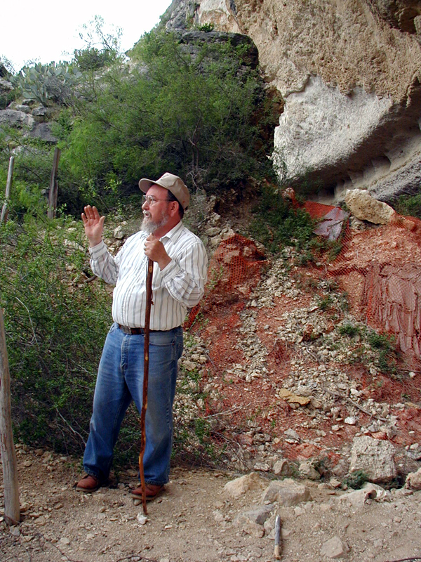 Elton Prewitt stands below the south end of Bonfire Shelter and recounts the excavation of Bone Bed 3. Behind him is the talus cone below the notch in the cliff through which hundreds of bison fell. 