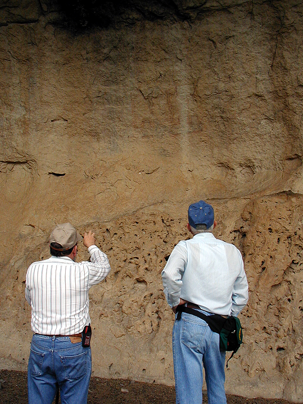 Elton Prewitt and Jack Skiles look at faded pictographs - painted images -- on the protected wall of Kelly Cave. 