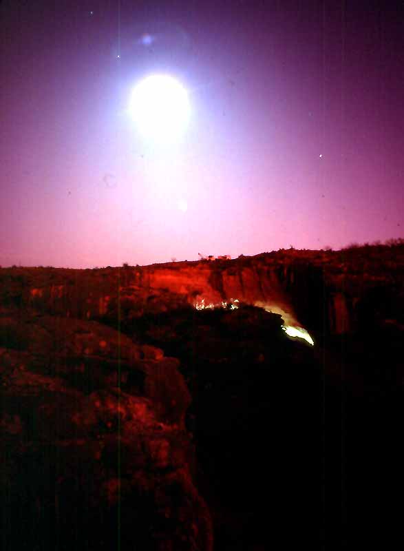Moon rising above Bonfire Shelter during the 1983 Excavations. A generator provided the florescent light emerging within the shelter and allowed the crew to work longer hours. Photo by Jack Skiles.