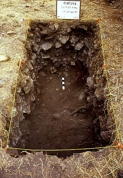 Photo of rectangular excavation trench with fire-broken rocks visible in the trench walls.