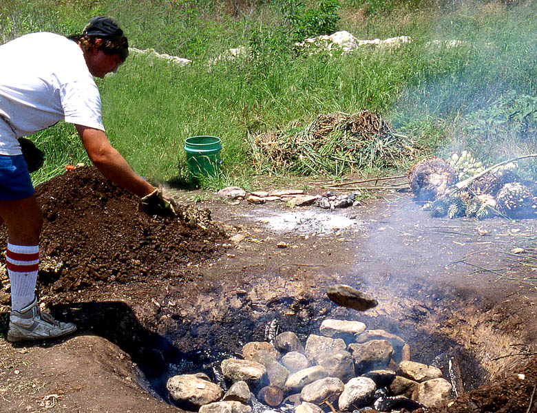 Photo of man tossing rock into a smokey pit lined with rocks.