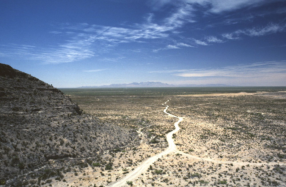 The Hueco Bolson; view west/northwest from Ceremonial Cave. Creosote, mesquite, and cacti cover the desolate sandy country. There are few nearby sources of water, although run-off from the hills provides seasonal moisture. It was sufficient apparently for Late Prehistoric peoples such as those at nearby Firecracker Pueblo to engage in small-scale farming of corn and other crops. Photo by Darrell Creel.