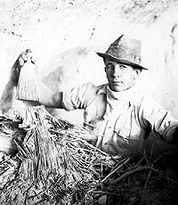 Famous picture of archeological assistant at Fate Bell Shelter, 1932, holding modern whisk broom above prehistoric fibers. Photo from ANRA-NPS Archives at TARL.