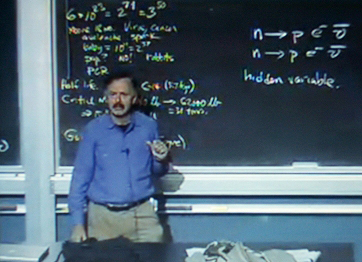 color photograph of a man in front of a chalkboard with mathematical equations on it