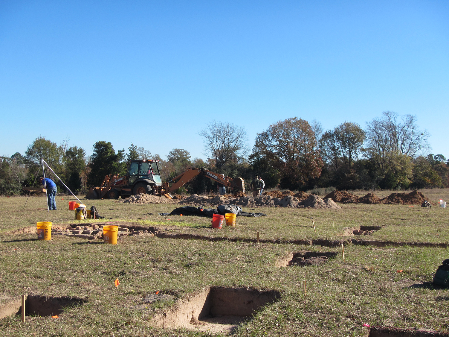 Photo of archeologists digging shovel tests in middle of open field