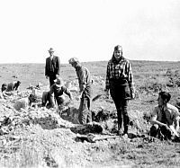 B&W photo of dig scene with a mix of workers and better-dressed individuals.