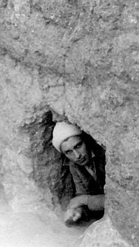 B&W photo of young man sticking his head ouf of small passageway.
