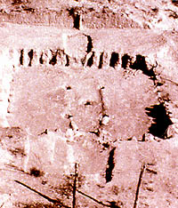 Oblique photo showing rectangular outline of the lower walls of a house marked by impressions or indentations where picket-posts once stood.