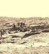 Sepia colored photo showing large group of me working on dig spread across sloping terrain.