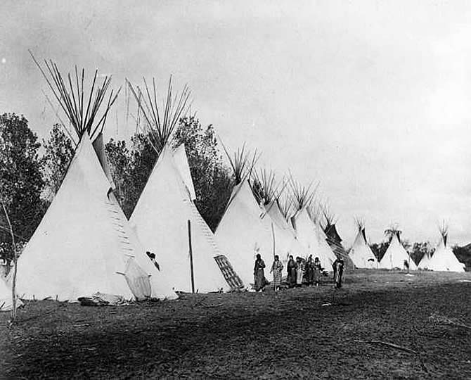 black and white photo of tipis in a row