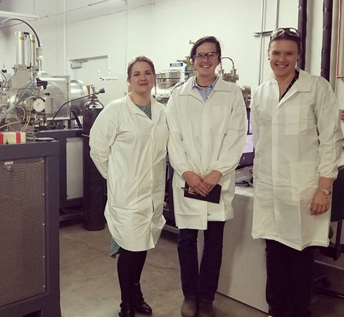 photo of three women in lab coats in front of equipment