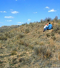 Photo two men looking closely at the wall of a dry arroyo.